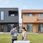積水ハウスの鉄骨造と木造（シャーウッド）の住宅が並び、どちらを選ぶか悩んでいる日本の夫婦が家の模型を見ている