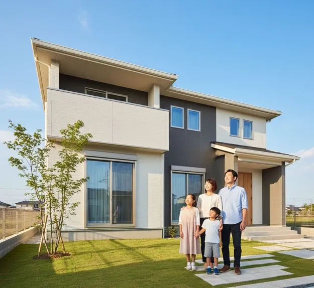 損傷のない積水ハウスの二世帯住宅の前に立つ家族(夫婦と二人の子供